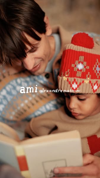 This image ad features a father and child reading a book together, promoting the brand Ami Alexandre Mattiussi. The ad f