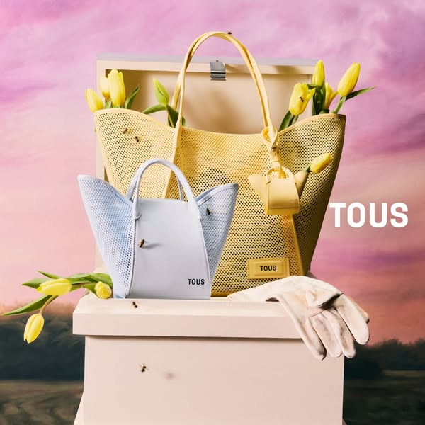 An image ad featuring the TOUS brand and two of its net bags. The bags are displayed on a white pedestal, surrounded by