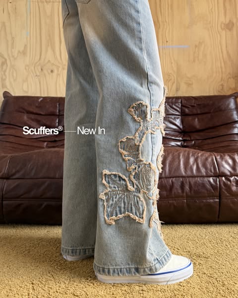Image promoting a pair of light-wash denim pants with patchwork floral detailing.