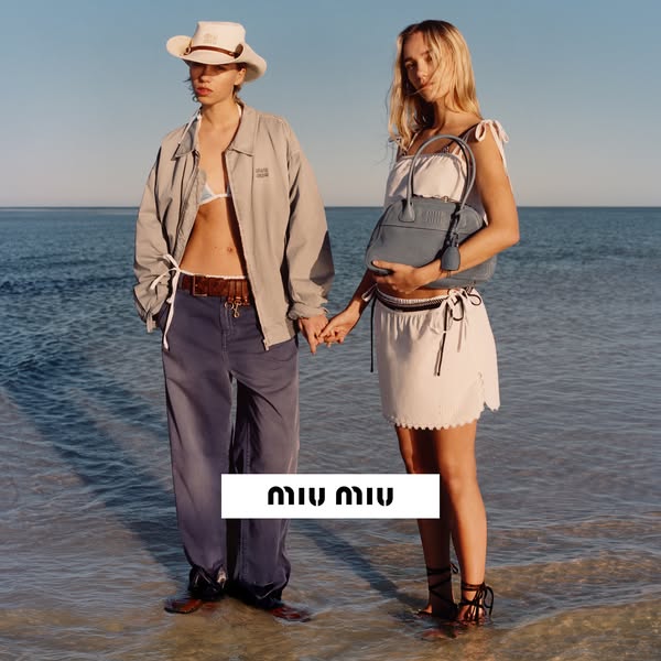 This ad showcases the brand Miu Miu, featuring two models on a beach with a handbag.