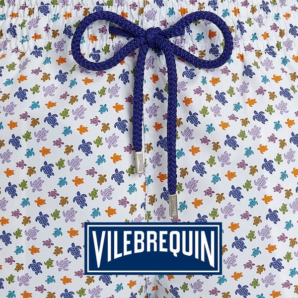 This image ad showcases Vilebrequin swim trunks patterned with turtles against a white background. The brand logo is dis