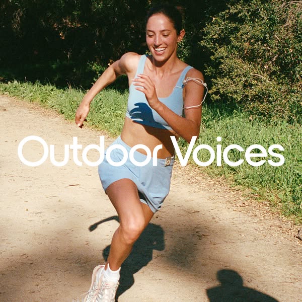 An image ad for Outdoor Voices athletic apparel featuring a woman running on a trail.
