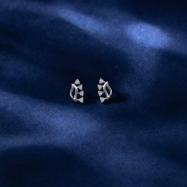 This ad showcases a pair of silver earrings with small stones on a blue background.