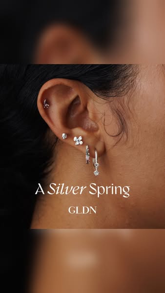This ad features a close-up of a person's ear adorned with multiple GLDN earrings and the copy "A Silver Spring