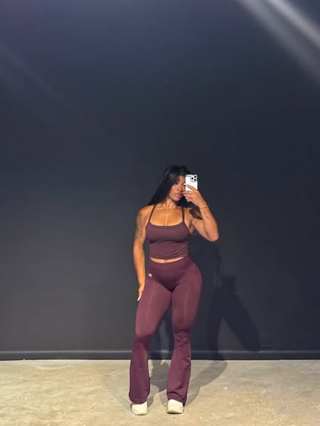 This image ad features a woman taking a mirror selfie while wearing a matching workout set. The ad is designed to showca