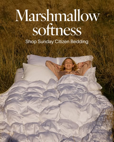 This image ad for Sunday Citizen bedding features a woman lying in bed in the middle of a field. The ad promotes a feeli