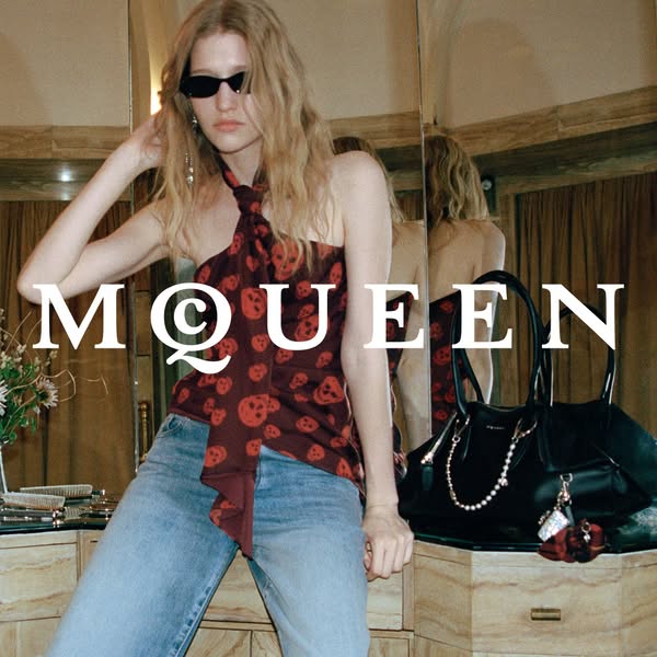 This ad features a woman wearing a skull-print top and jeans, accessorized with sunglasses and a black handbag. The bran