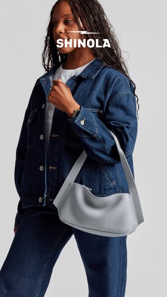 This ad features a woman modeling a gray leather Shinola bag. The brand name is displayed above the woman.