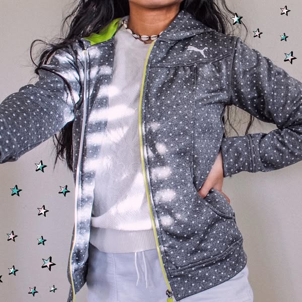 This ad features a person wearing a Puma brand jacket. The jacket is gray with white polka dots and a neon green zipper 