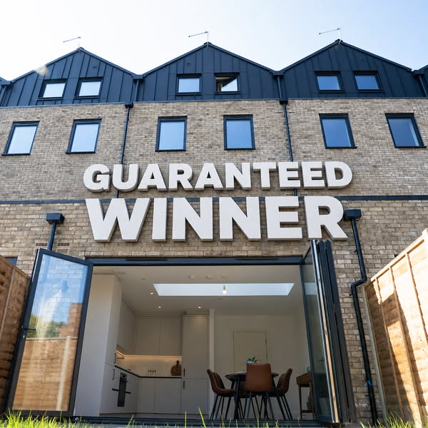 An image ad for real estate homes. The ad showcases the exterior of modern brick townhomes with a large 'GUARANTEED 