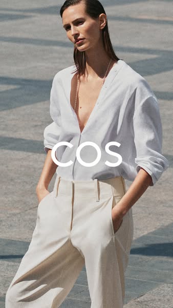 A woman wearing a white linen shirt and beige slacks in an outdoor setting with the COS logo centered on the image.