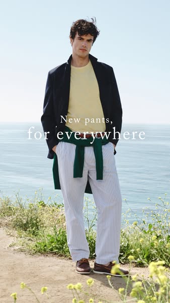 An image ad for men's pants featuring a male model in a navy jacket, yellow t-shirt, and blue-striped pants, with a 