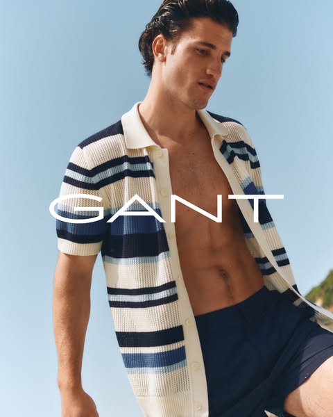 The ad showcases a man wearing a striped knit short sleeve shirt and swim trunks, both from GANT, against a sunny outdoo