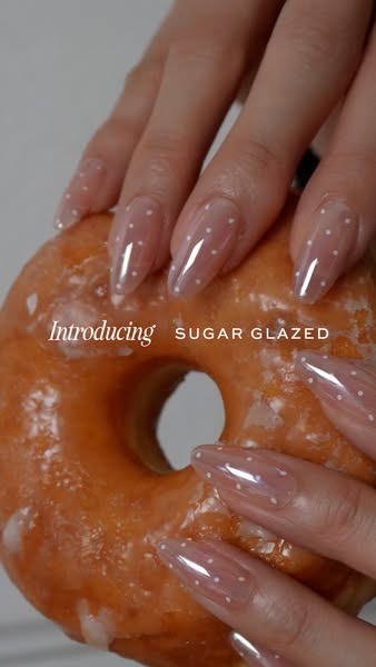 This ad showcases a new nail polish color called Sugar Glazed. The ad features a hand with long, almond-shaped nails pai
