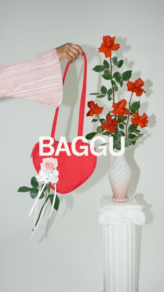 This ad features a red heart-shaped Baggu bag with a small floral decoration, presented in a lifestyle setting with a ne