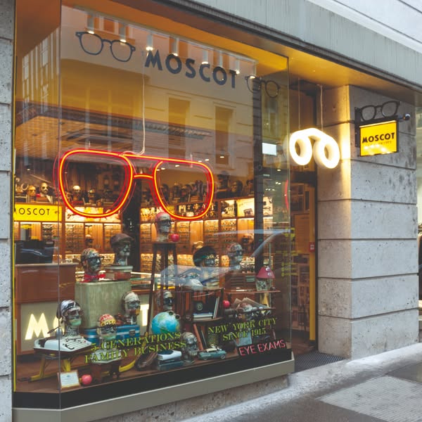This ad showcases the storefront of a Moscot store, emphasizing its heritage and eye exam services.