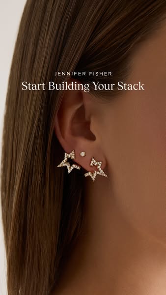 The image ad features a close-up of a model's ear wearing a stack of Jennifer Fisher earrings. The ad encourages vie