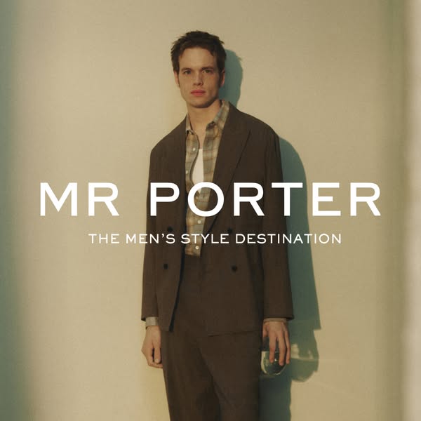 This image ad for Mr Porter features a man in a brown suit and plaid shirt, standing against a neutral wall. The ad prom