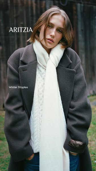 This image ad from Aritzia features a model wearing a winter outfit that includes a wool coat, cable knit sweater, and s