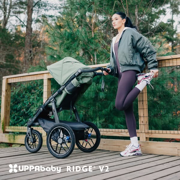 This ad features a woman stretching next to a UPPAbaby Ridge V2 stroller in a natural outdoor setting, highlighting an a