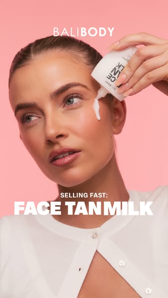 A close-up shot of a model applying Face Tan Milk from Bali Body, with text that says, "Selling fast: Face Tan Milk