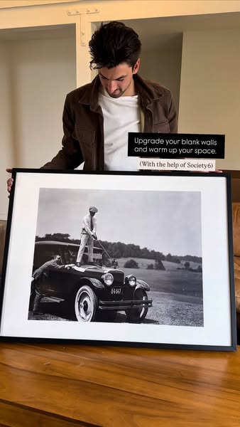 Man shows off Society6 framed art that he is using to decorate his space.