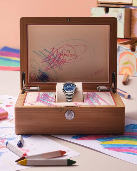 This image ad showcases a luxury Omega watch displayed inside a wooden box, with the inside of the box and surrounding p