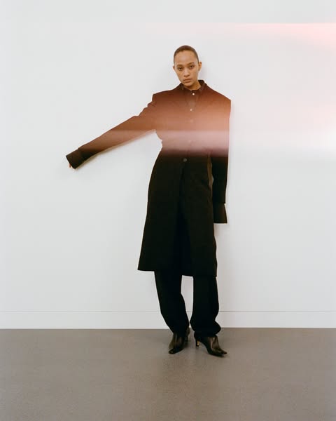 This ad features a woman in a black outfit standing against a white wall. The ad is likely for a fashion brand.