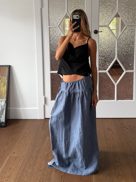 This ad features a woman taking a photo of herself in a mirror wearing a black tank top and a long blue and white stripe