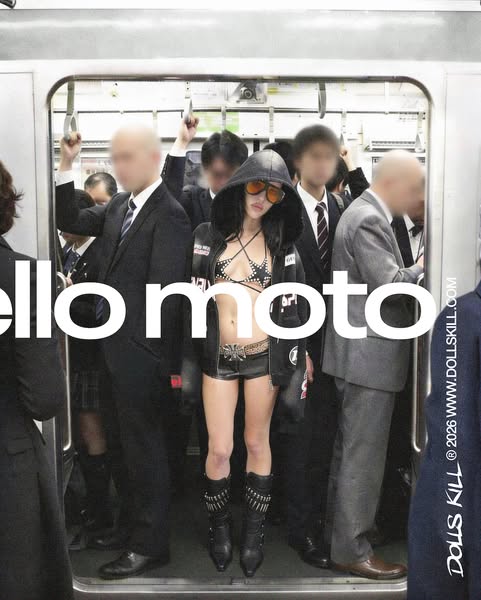 This image ad for DOLLS KILL features a model wearing a bikini top, jacket, shorts, and boots from the brand while stand