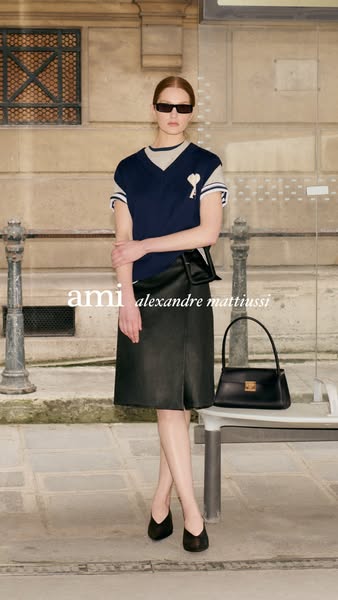 This ad features a woman wearing Ami clothing and carrying an Ami handbag, standing on the street.
