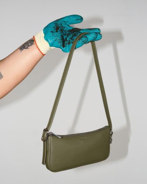 This ad showcases a purse and the brand through the use of a dirty gardening glove holding the purse.
