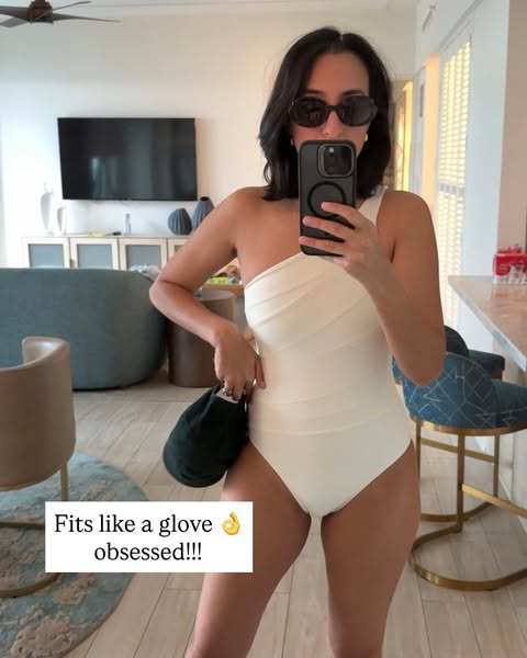 This ad features a woman in a white swimsuit taking a selfie in what appears to be her home. She is holding a dark green