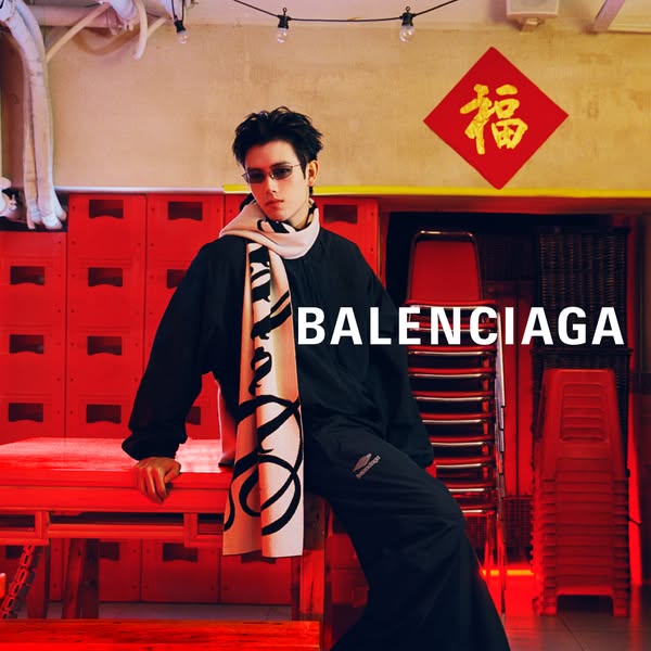 This ad features a person wearing Balenciaga apparel in a red-toned room. The Balenciaga logo is prominently displayed i