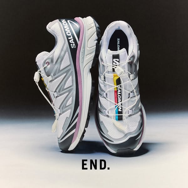 An image of two white and grey athletic shoes, one positioned sideways and one facing forward, against a gradient grey b