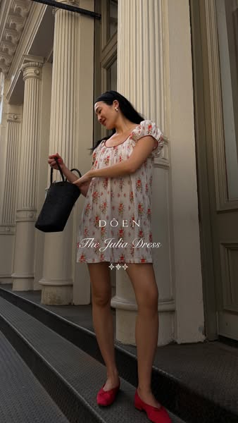 This ad features an outdoor shot of a woman wearing a white floral dress and red flats while holding a black bucket bag.
