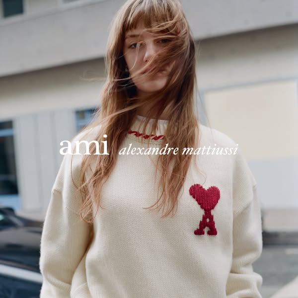 This ad features a woman wearing an AMI Alexandre Mattiussi sweater. The shot is taken at eye-level and shows the subjec
