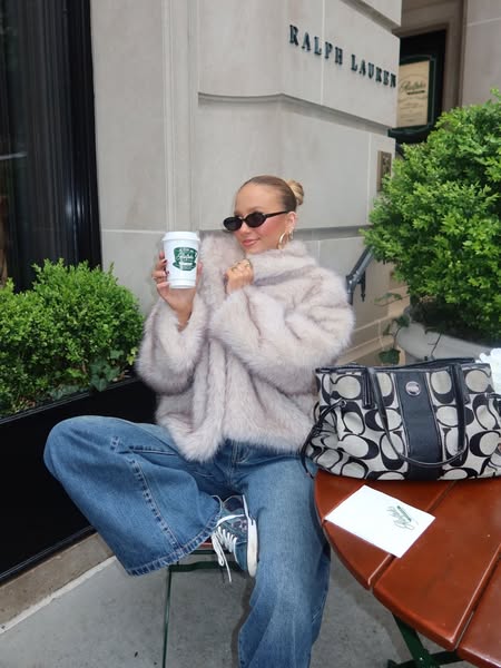 The ad features an influencer sitting on a cafe patio who is holding and showcasing a coffee cup with a logo. The influe