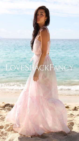 This ad features a LoveShackFancy dress worn by a model on a beach. The scene evokes a sense of luxury and escape, appea