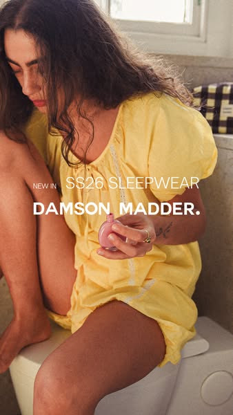 This ad for Damson Madder sleepwear showcases a woman in a yellow pajama set with lace detailing, sitting on a closed to