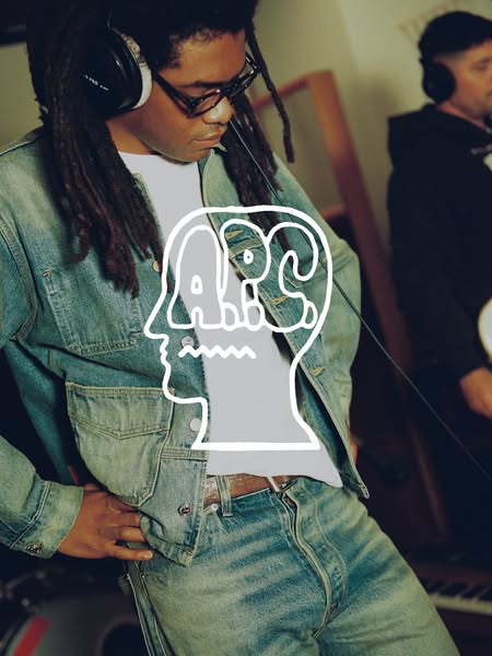 This ad features a man wearing glasses, headphones, and a denim jacket with matching pants. The man is standing in a stu