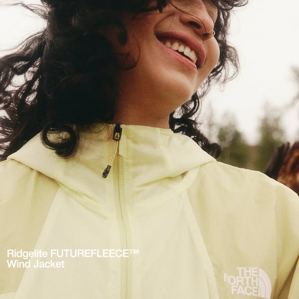 This image ad showcases a woman happily wearing a Ridgelite FUTUREFLEECE™ Wind Jacket from The North Face. The ad focuse