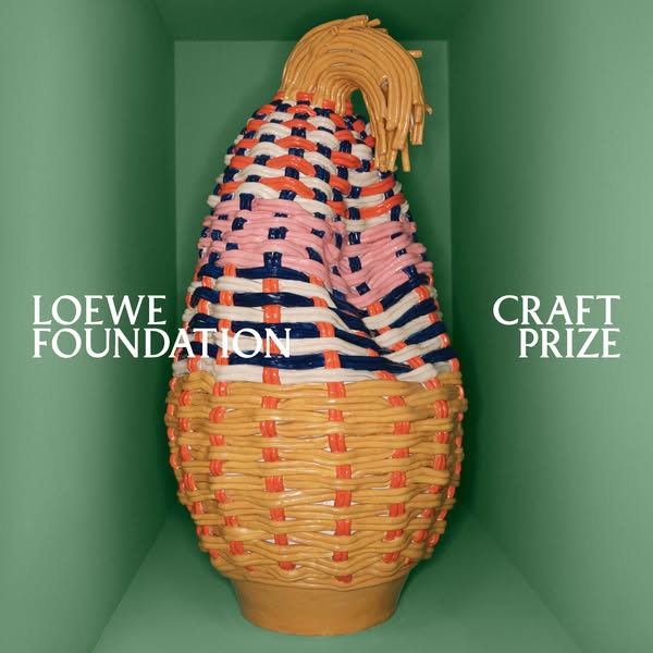 This image ad promotes the LOEWE Foundation Craft Prize. The ad features a large, colorful woven sculpture inside a gree