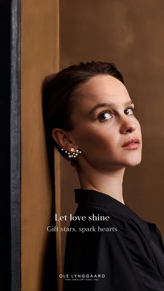 This image ad for Ole Lynggaard Fine Jewellery features a woman wearing star-shaped earrings. The text overlay invites v
