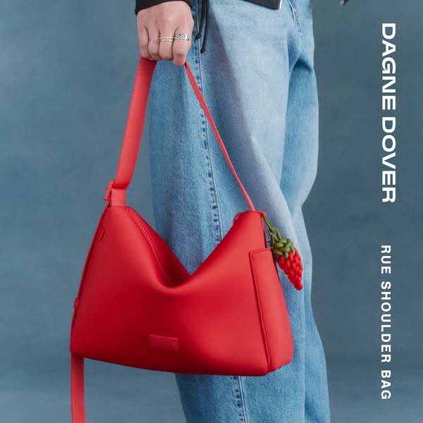 This image ad for Dagne Dover features their red Rue Shoulder Bag. It is displayed on a model and includes the brand and