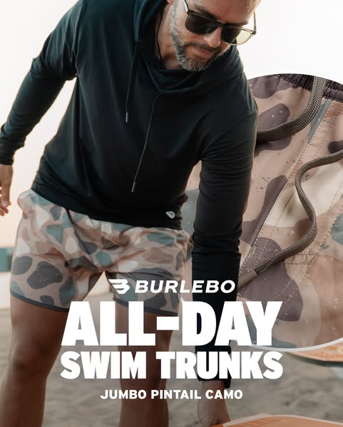 An ad for Burlebo swim trunks featuring a man on a beach wearing a black hooded long-sleeve shirt and Jumbo Pintail Camo