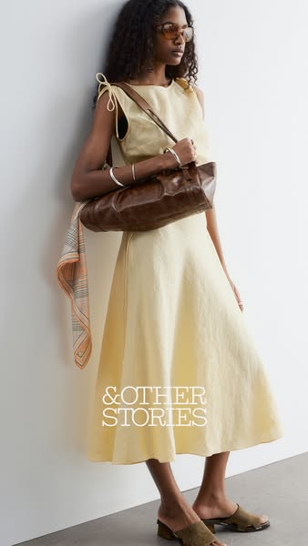 An ad shows a woman leaning against a white wall. She is wearing a yellow dress, brown purse, and shoes. The brand name 