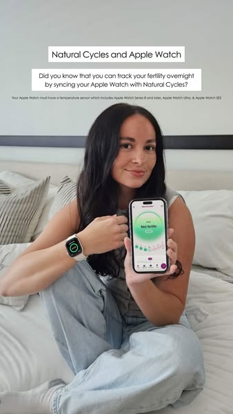 An image ad featuring a woman sitting in bed promoting the Natural Cycles app. The ad highlights the ability to track fe