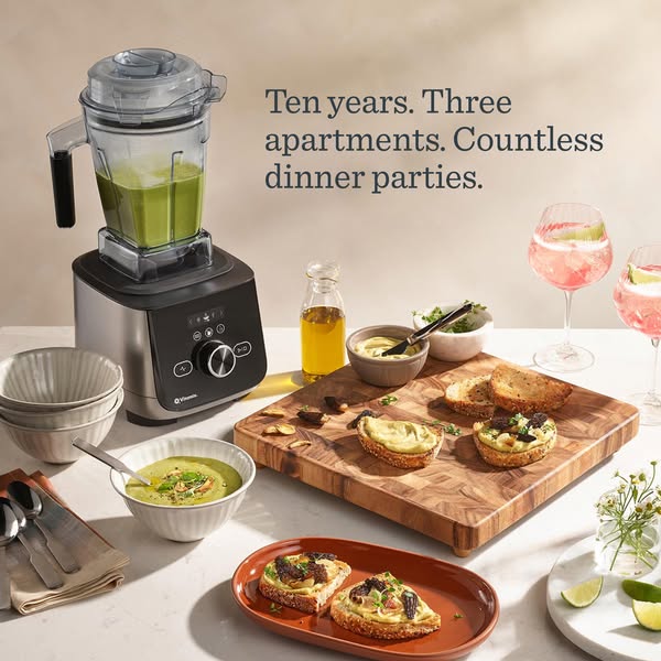 The ad features a Vitamix blender in a lifestyle setting with various prepared foods and cocktails, emphasizing its role