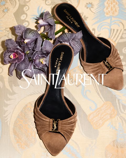 This image showcases a pair of Saint Laurent heels, placed next to a bouquet of flowers on a patterned background, and i